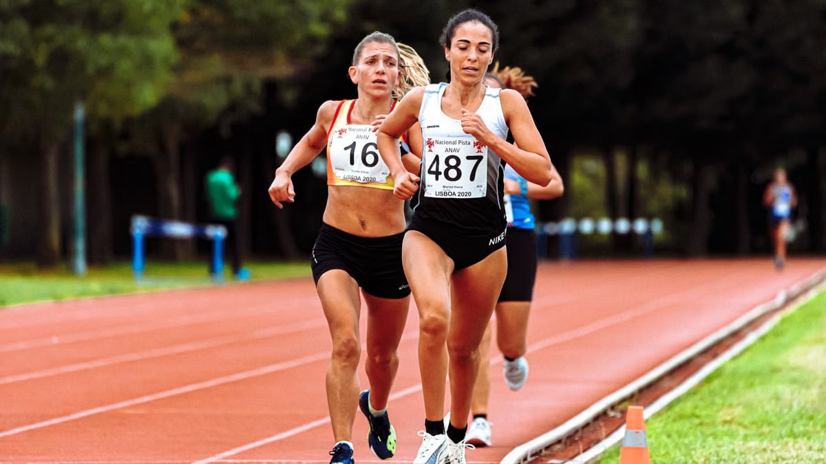 Young sportswomen in active wear with numbers running while participating in track and field athletics competition